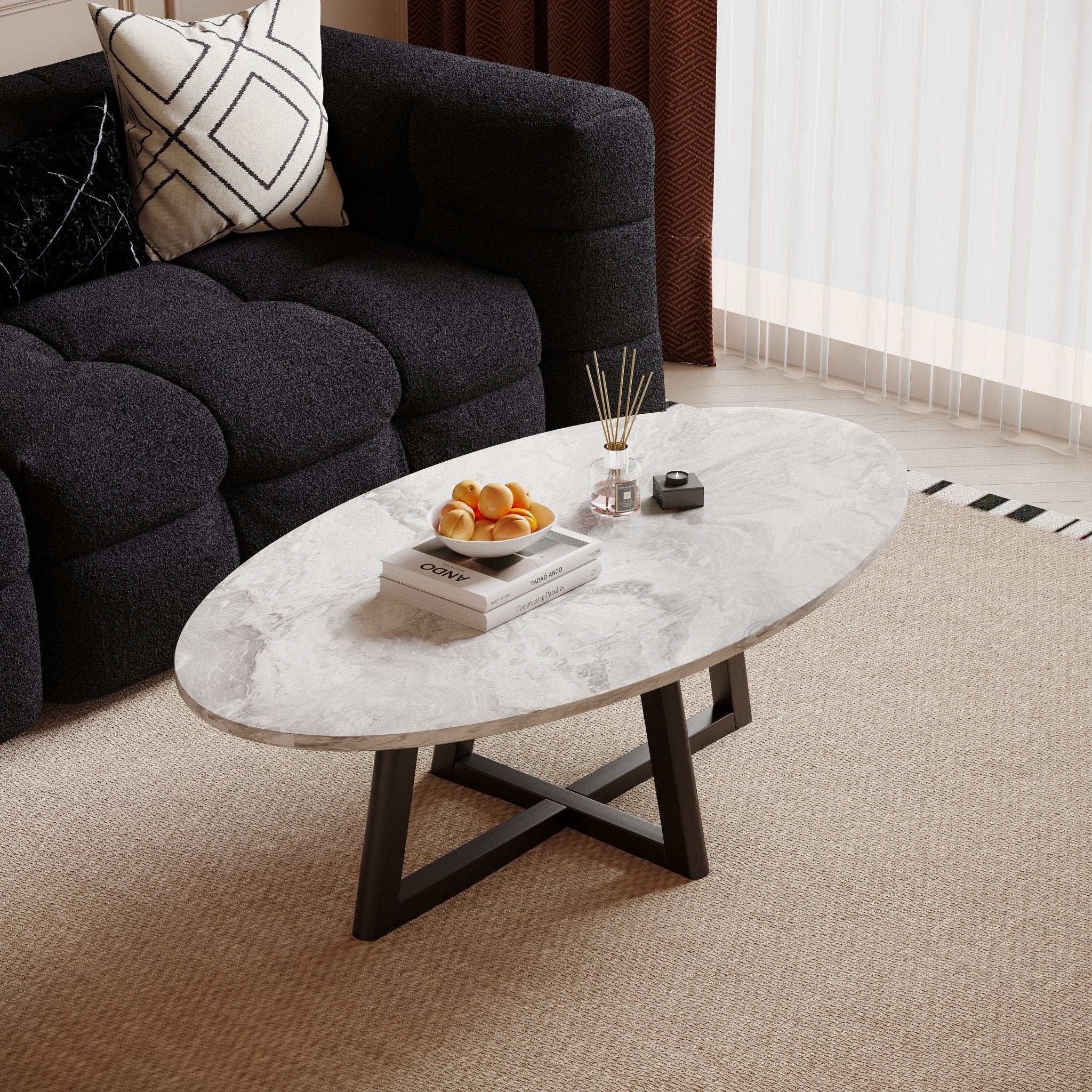 Morra oval marble-effect coffee table with black cross base beside a dark sofa