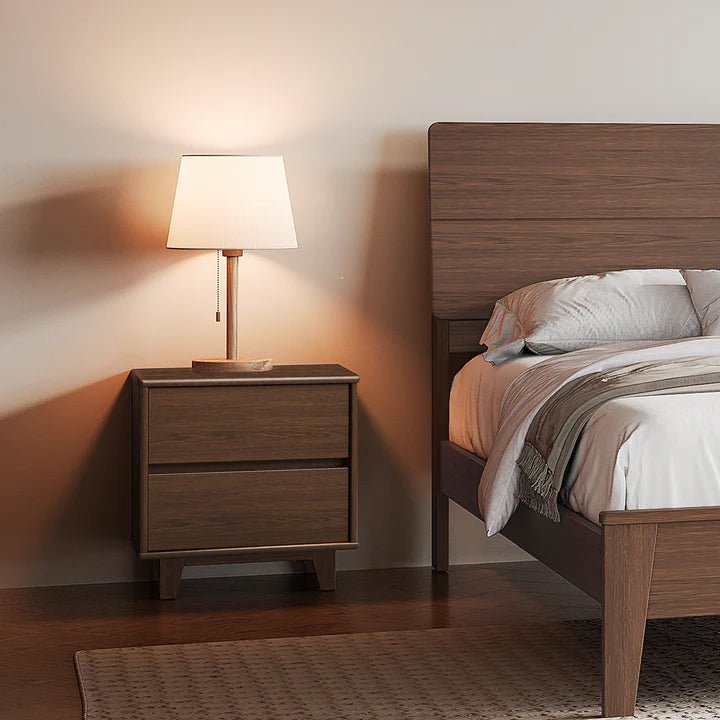 Arezzo walnut bedside table with two drawers and angled legs beside a bed