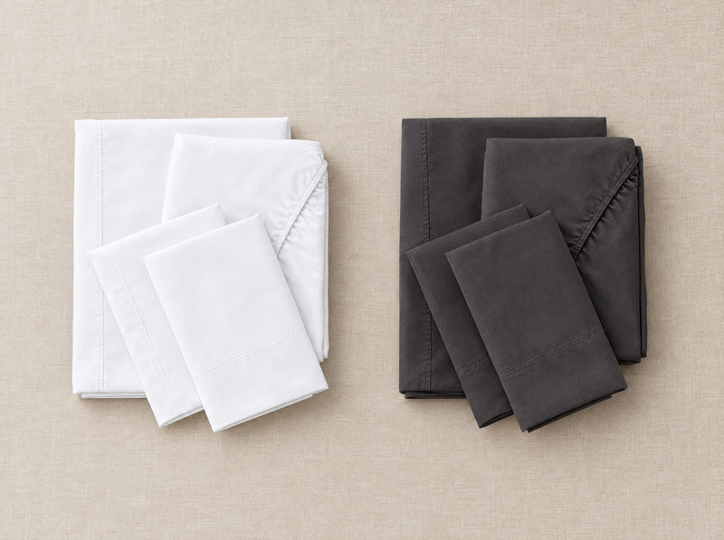 White cotton-blend sheet set folded on an Olympic Queen bed
