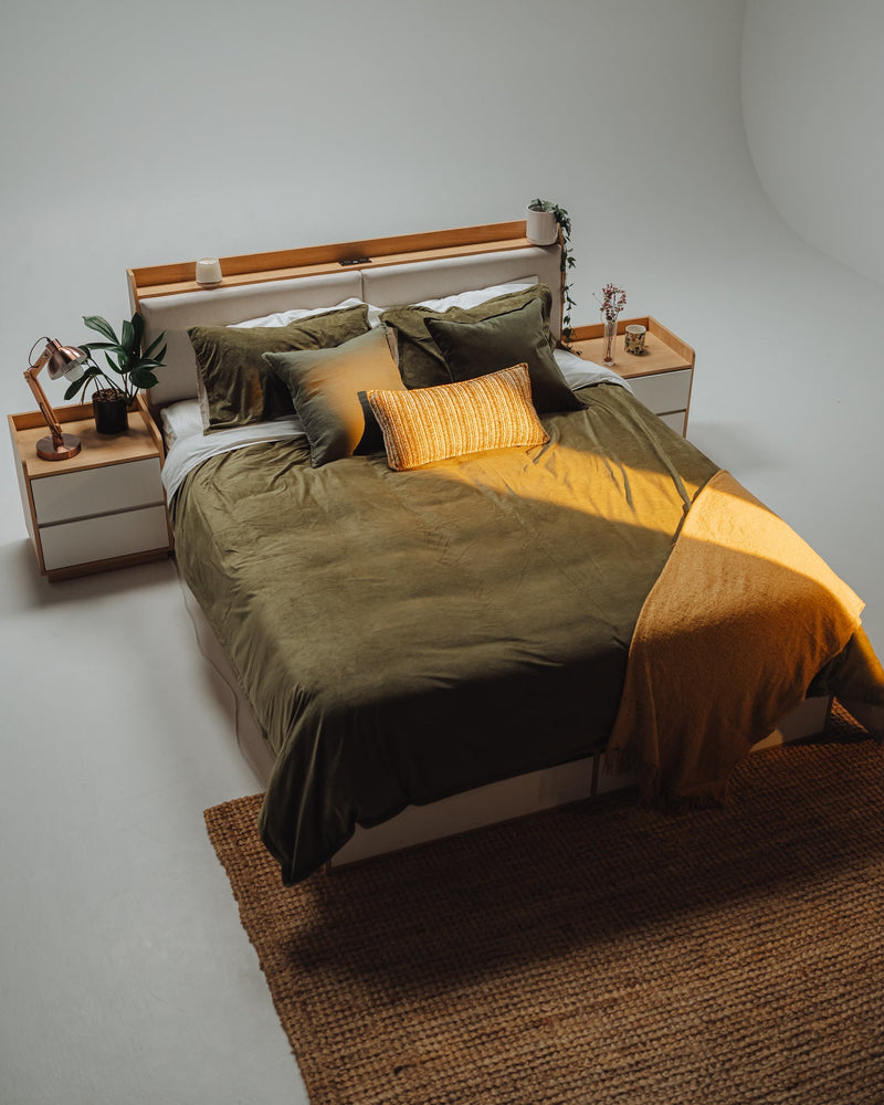 Turin gas lift storage Oak bed frame with headboard shelf and two matching bedside tables in a styled bedroom with charger