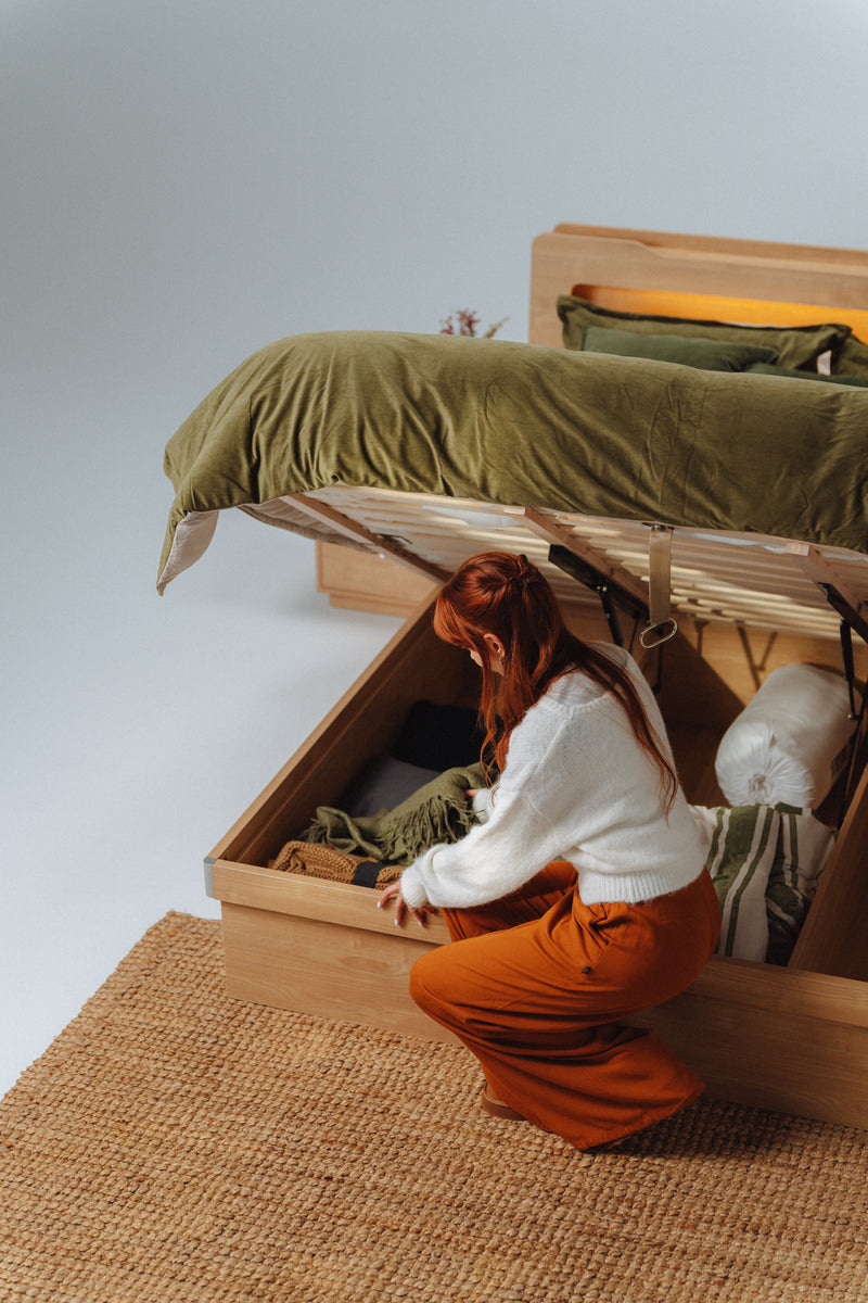 Doria Light oak gas-lift storage bed frame with the base lifted open in a bedroom