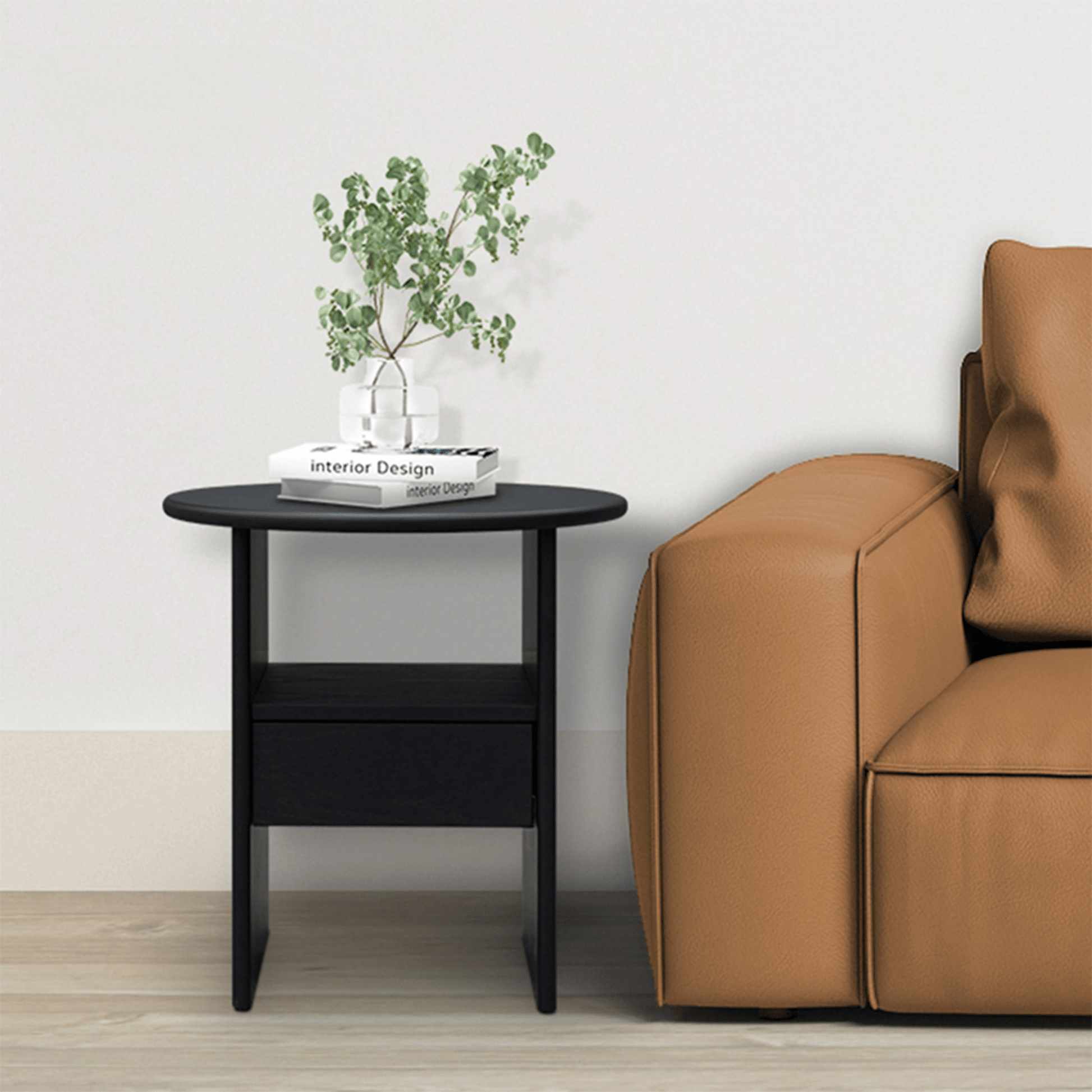 Ranco round black side table with drawer and shelf beside a tan leather sofa
