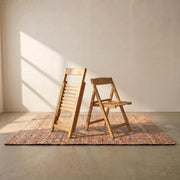 Lecce light wood folding chairs set up on a rug in a sunlit room